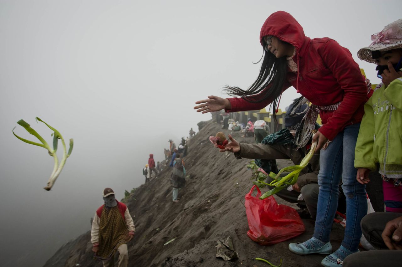 A worshipper throws an offering of vegetables into the caldera. Hundreds of people travel to the volcano to pray on the 14th day of the festival.