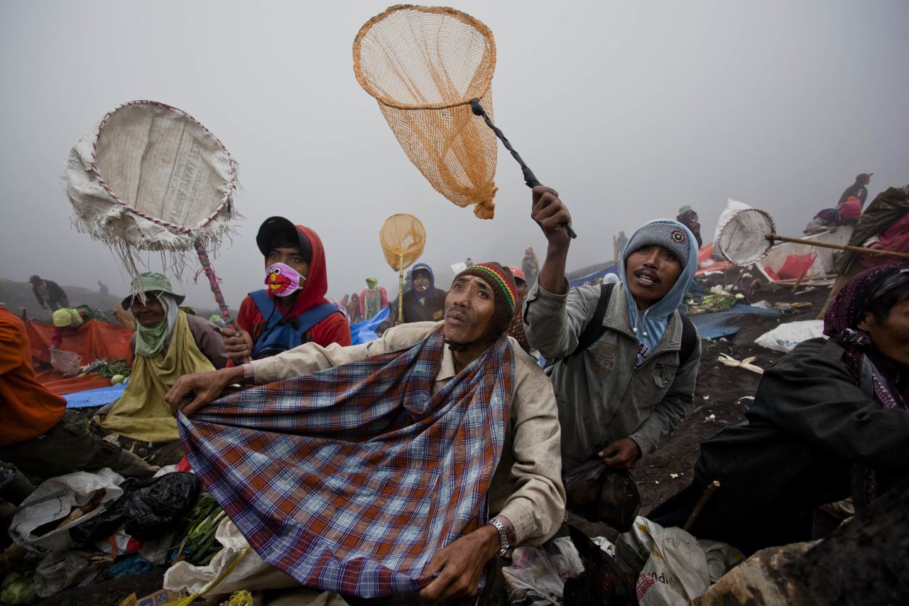 While the worshippers throw their offerings into the volcano, local villagers gather under the edge of the crater, trying to catch some of the food in nets.