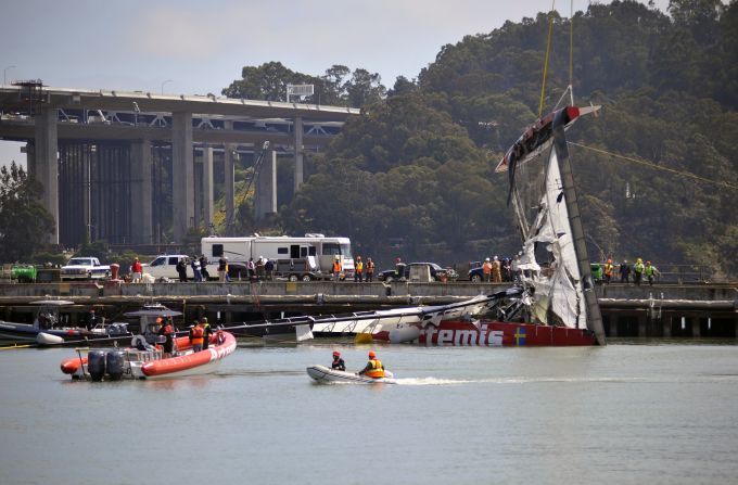 The high-speed AC72 capsized, trapping Simpson under the hull. Here a crane lifts the stricken vessel out of the dock.