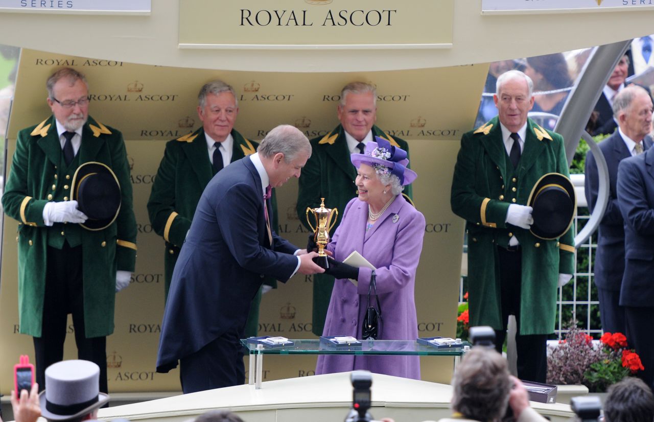 Queen Elizabeth II receives the Royal Ascot Gold Cup from her son Prince Andrew after her horse Estimate won the 2013 edition of the prestigious race.