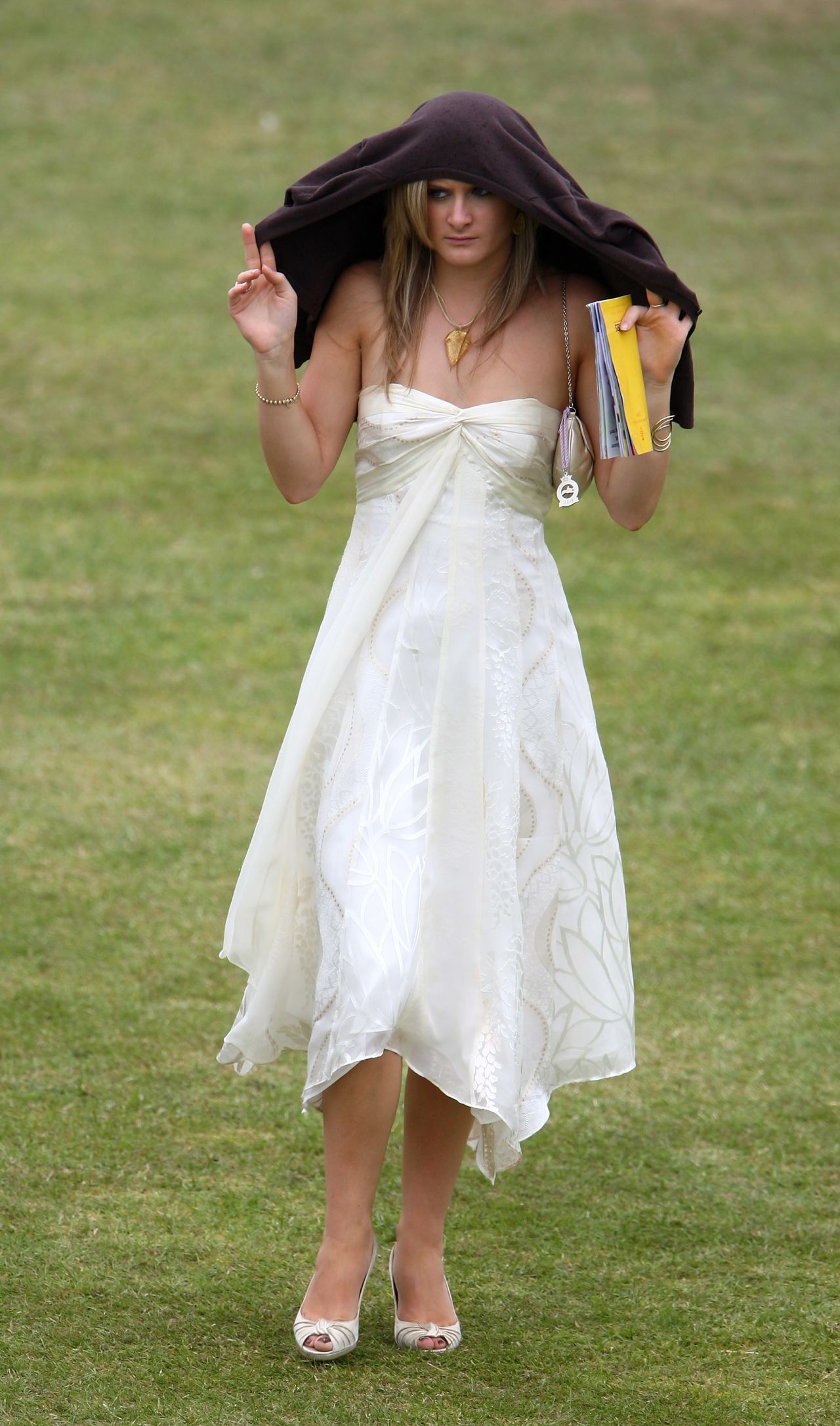 A female racegoer shelters from the rain at Glorious Goodwood where the English summer can often bring inclement weather.
