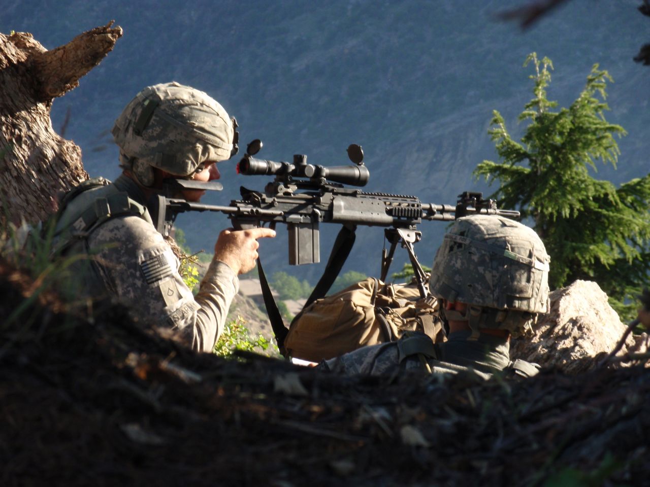 Carter with Spc. John Adams on their first patrol in Afghanistan. They are observing the Village of Kamdesh from a ridgeline between Observation Post Fritsche and the village.