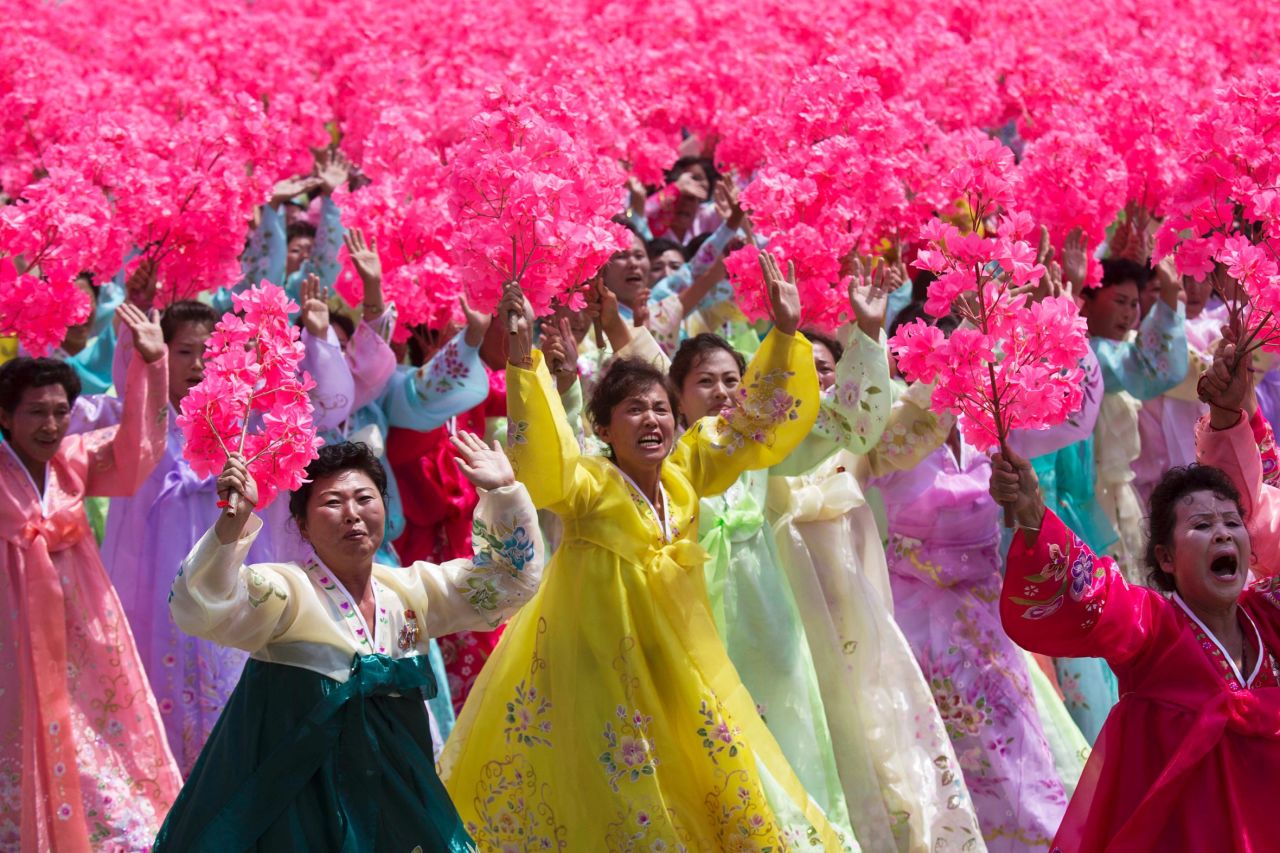 Women participating in the parade wave as they pass Kim Jong Un on July 27.