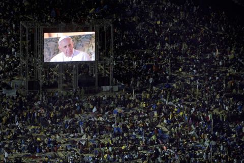 The pope's image is broadcast on screens throughout the crowd. 