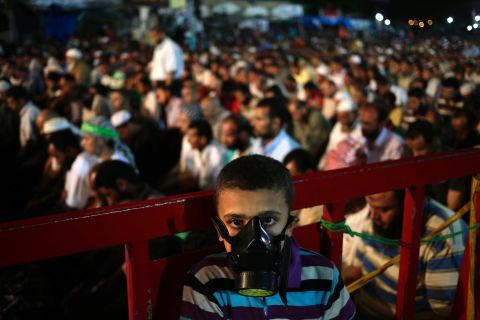A boy wears a tear gas mask as supporters of Egypt's ousted President Mohammed Morsy pray at the camp set up by supporters in the Nasr City area of Cairo on July 28.  