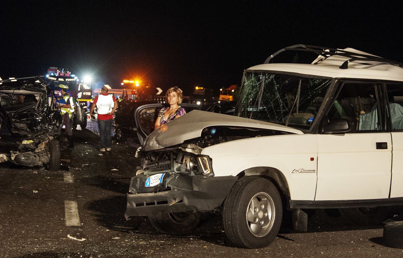 Damaged cars and debris litter the scene of the accident. 