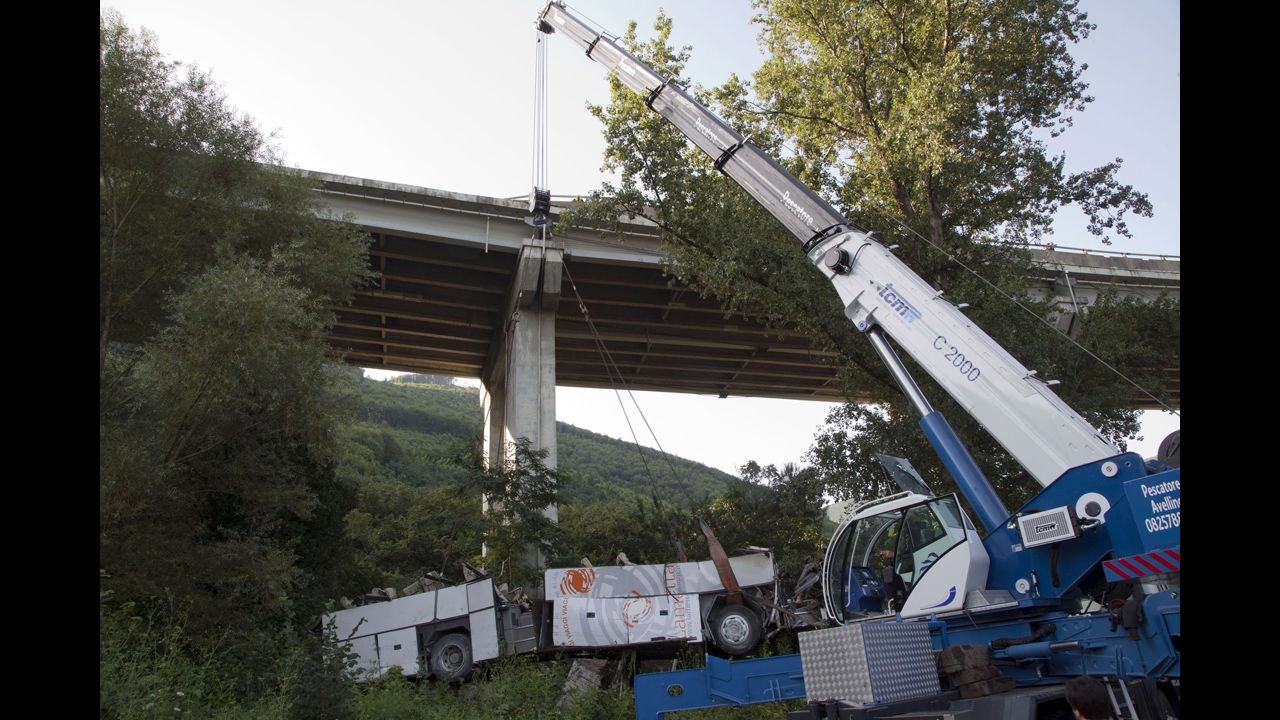 Workers remove the wreckage of a bus on Monday, July 29, near Baiano, Italy. The bus was returning pilgrims from a weekend visit to a Catholic shrine when it went off a bridge in southern Italy on Sunday, July 28, killing dozens of passengers, including some children, officials said. 