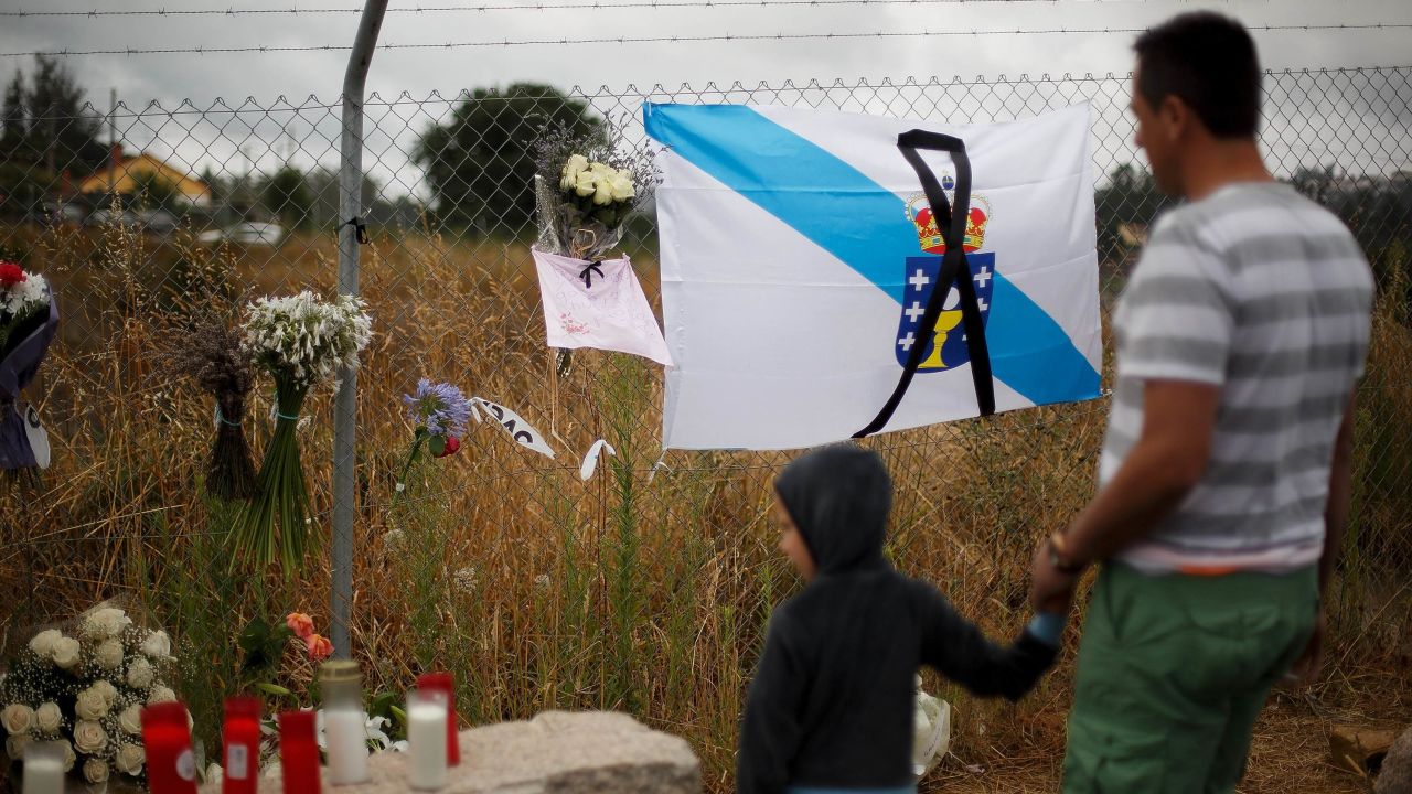 A man and child survey a memorial including a Galician flag on July 28.