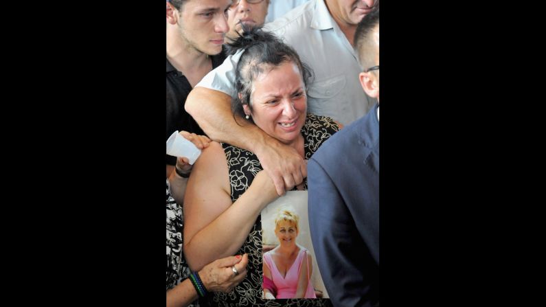 A distraught woman holds a picture of a crash victim at the funeral July 30.
