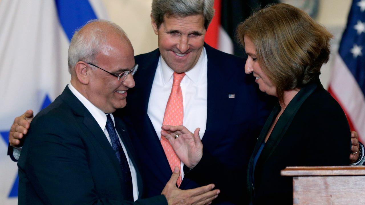 John Kerry (C) looks on as Israeli Justice Minister Tzipi Livni and Palestinian chief negotiator Saeb Erekat (L) shake hands.