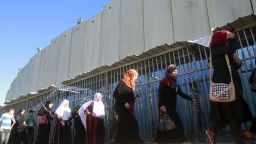 Palestinian Muslim worshipers walk alongside Israel's controversial separation barrier on the outskirts of the West Bank town of Bethlehem as they undergo security checks by Israeli security forces before heading to Jerusalem to attend Friday prayers at the Al-Aqsa mosque compound on July 26, 2013 during the Muslim fasting month of Ramadan.
