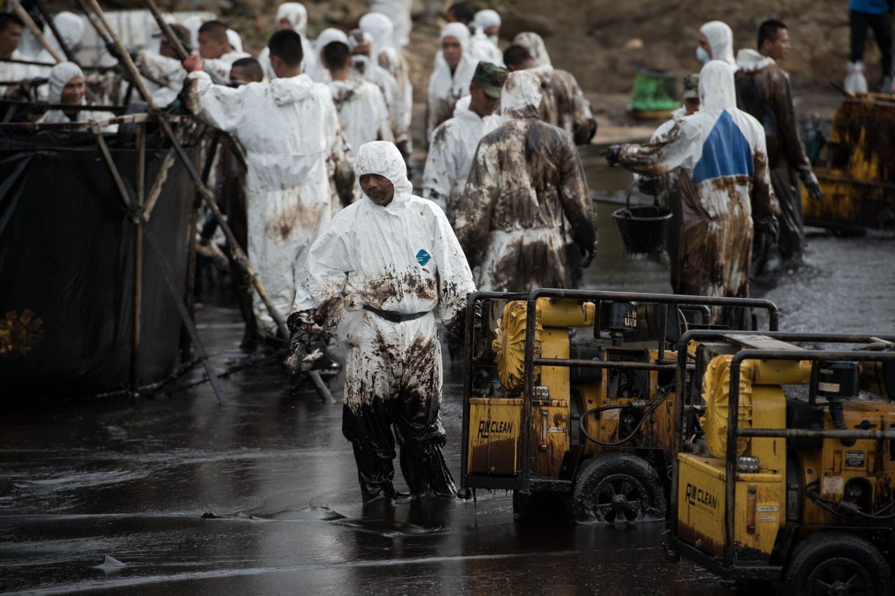 Thai navy personnel are splattered with oil as they work to clean up Ao Phrao beach on July 30.