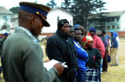 A policeman stands as Zimbabweans line up near a polling station in Harare. Zimbabwe was readying for an inadequately prepared yet tight election battle that could see President Robert Mugabe extend his 33-year grip on power.