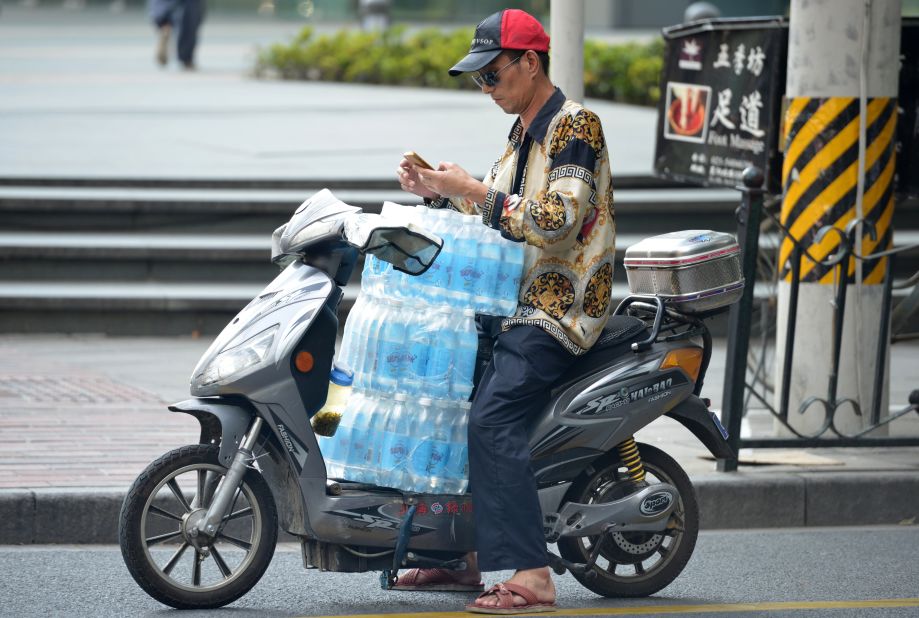 A man ferries several cases of bottled water on his scooter as a heat wave continues in Shanghai on July 24.