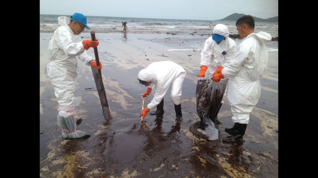 Workers continue to remove oil from Koh Samet on Thursday, August 1. PTT Global Chemicals says the Thai navy and approximately 300 PTT workers are continuing to clean up the area.