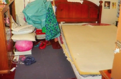 Toys and other belongings are piled in a bedroom.
