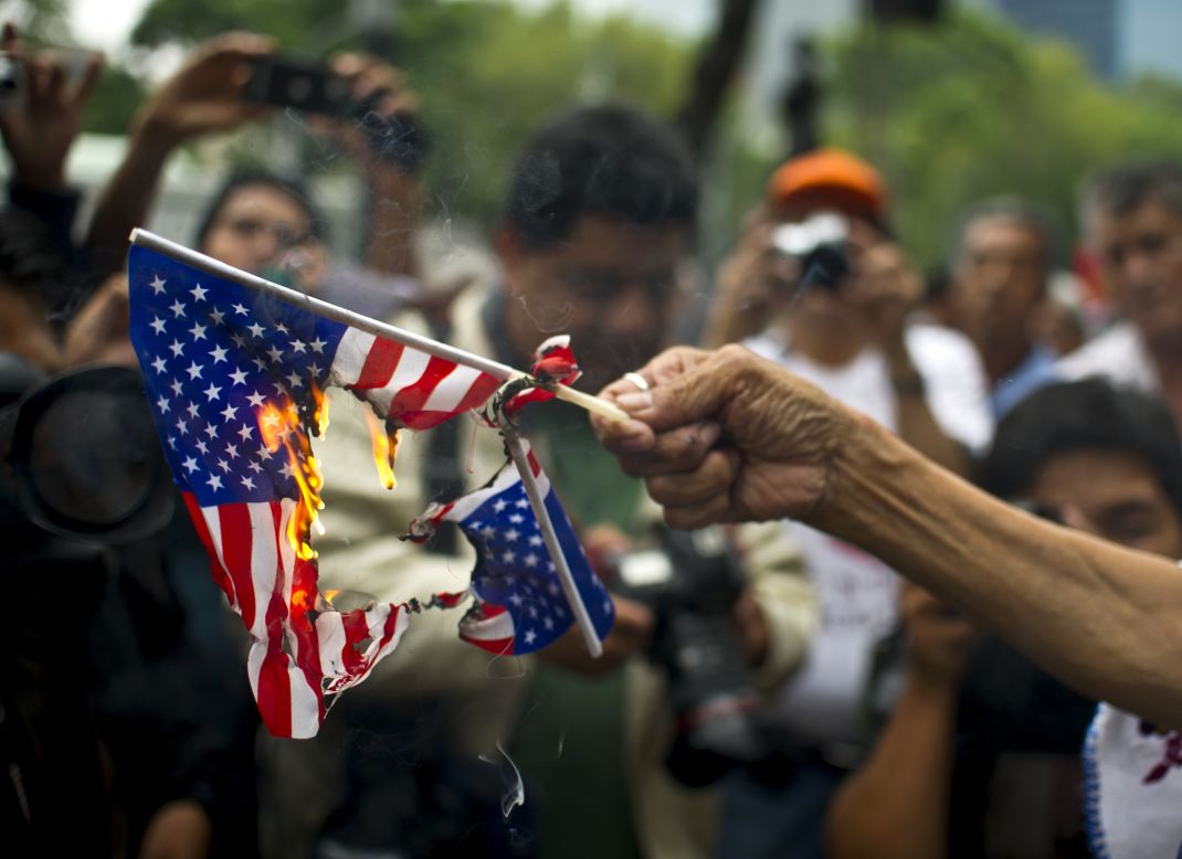A woman burns American flags during a protest in support of Bolivian President Evo Morales in front of the U.S. embassy in Mexico City on July 4. Leftist Latin American leaders and activists were fuming after some European nations temporarily refused Morales' plane access to their airspace amid suspicions Snowden was aboard.