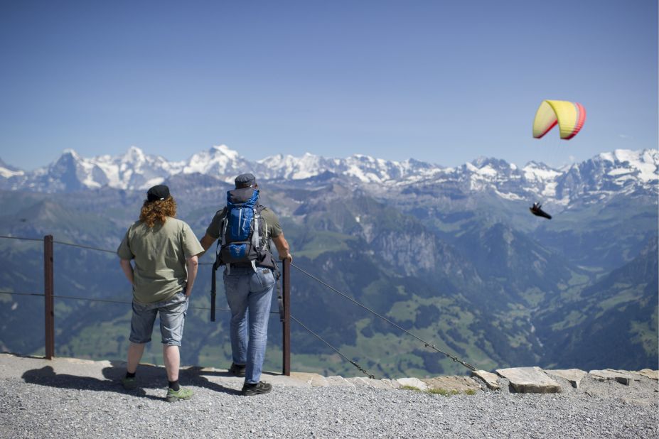 People watch a paraglider as they hike on the Niesen mountain in Switzerland, Friday, August 2. Temperatures reached 86 degrees Fahrenheit in central Switzerland. 