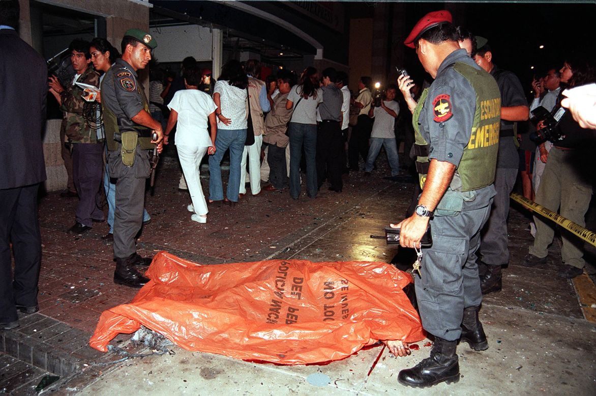 Police officers stand next to the body of a victim after a car bomb exploded on March 20, 2002, at a shopping center near the <a href="http://archives.cnn.com/2002/WORLD/americas/03/21/peru.embassy.blast/">U.S. Embassy in Lima, Peru,</a> killing nine people.