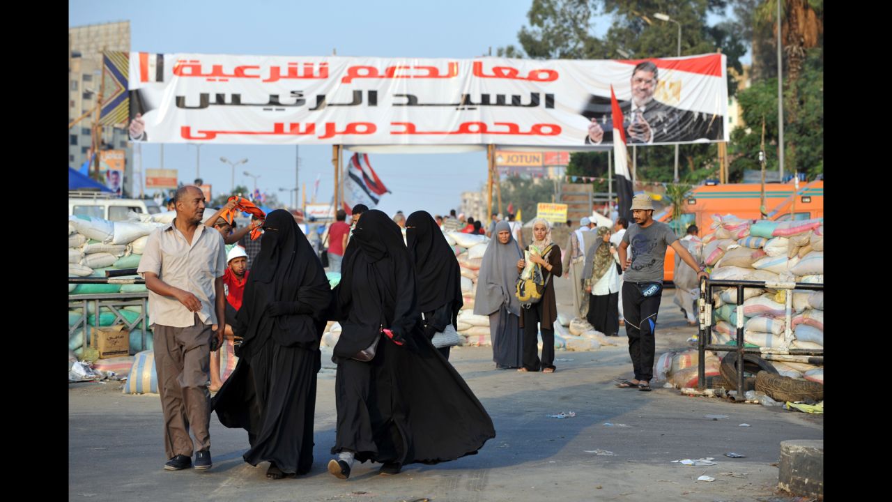 Morsy supporters walk past makeshift roadblocks at Rabaa al-Adawiya Square in Cairo on Saturday, August 3. Security forces set up the roadblocks outside the square, allowing people to leave but not enter, as they attempt to break up camps set up during ongoing protests over Morsy's ouster. 