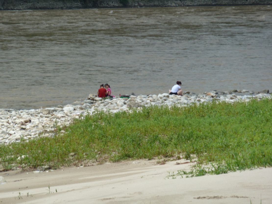 A North Korean family crouches by the river in Hyangsan, three hours from Pyongyang.