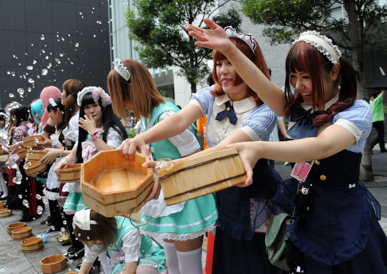 Women in maid costumes throw water to the ground in the Akihabara shopping district in Tokyo on Saturday, August 3. They were taking part in an annual summer event to cool off the street.      