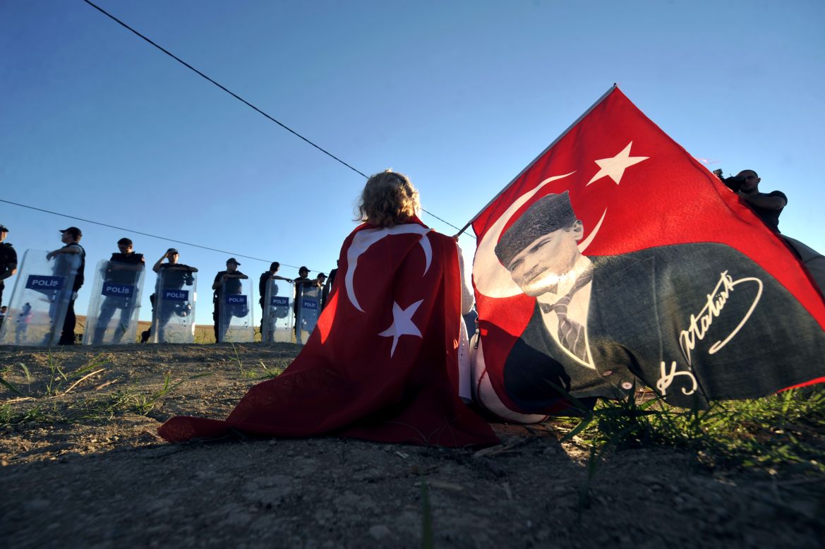 AUGUST 6 - SILIVRI, TURKEY: Holding a portrait of Mustafa Kemal Ataturk, Turkey's first president, a protester sits in front of police forces blocking access to a courthouse in Silivri, near Istanbul, on August 5. <a href="http://cnn.com/2013/08/05/world/europe/turkey-ergenekon-verdict/?hpt=wo_c2">Ilker Basbug, the former head of Turkey's military, was sentenced to life in prison Monday.</a> He is the most prominent figure accused of trying to overthrow the government.
