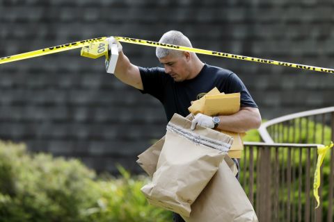An investigator carries evidence away from the Ross Township Municipal Building crime scene on August 6.