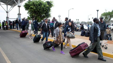 Travelers walk to be taken to hotels after the airport initially was closed August 7 following the fire. <br />