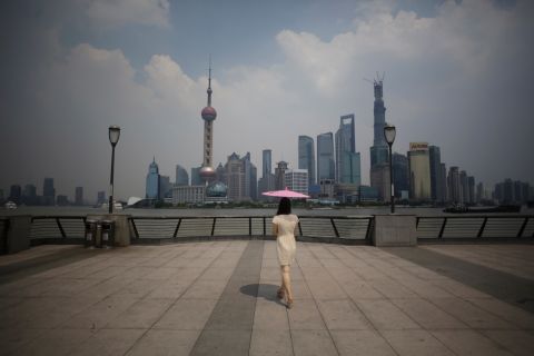 A woman uses a parasol to block the sun's rays at the Bund, a popular tourist spot in Shanghai, China, on August 7. 