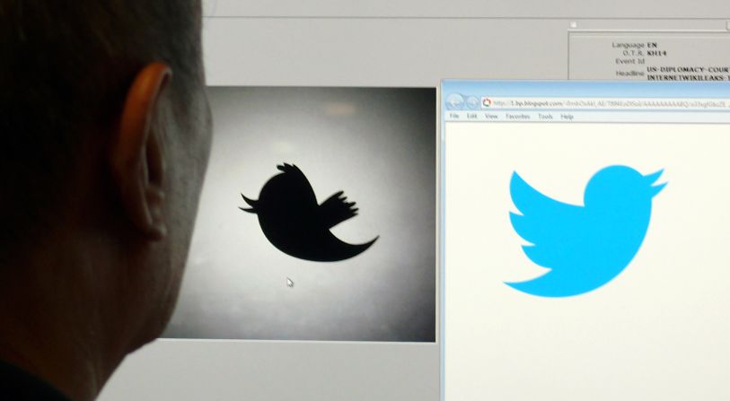 A man looks at a computer monitor showing the old and new Twitter logos. The social networking company dropped the name and now uses the bird image alone.