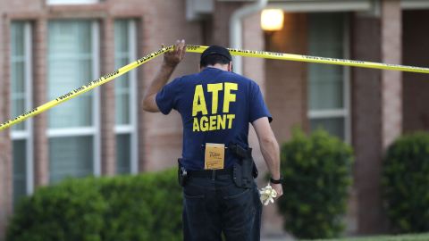 An ATF agent ducks under crime scene tape at a house in DeSoto, Texas.