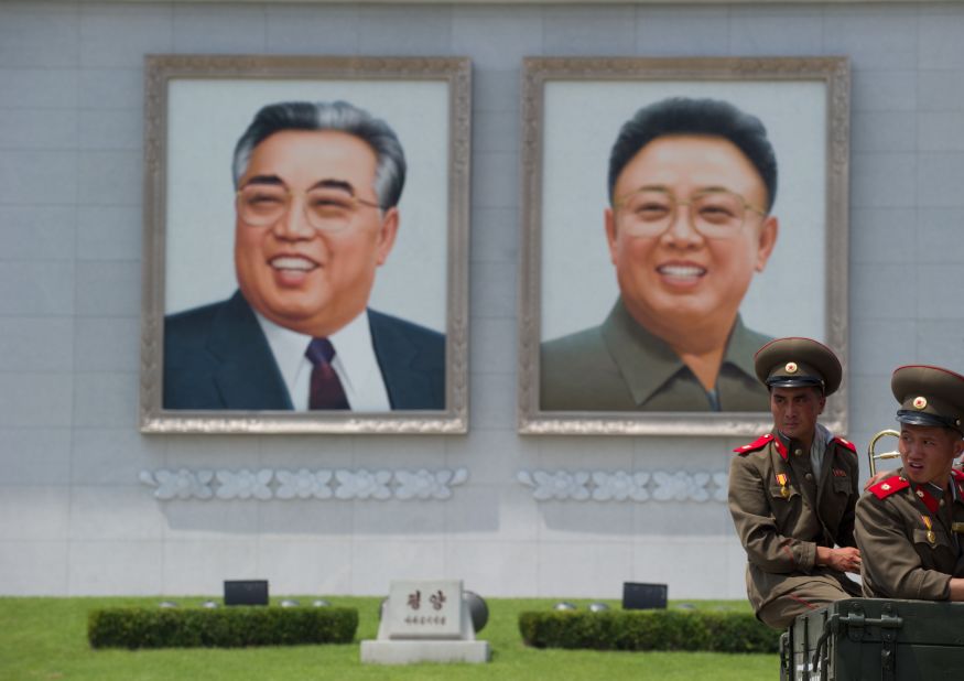 North Korean soldiers sit on the back of a truck on Kim Il-Sung square before portraits of former leaders Kim Il-Sung (l) and Kim Jong-Il (r). 