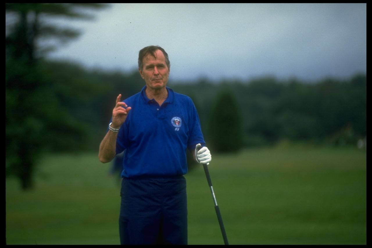 President George H.W. Bush pauses to speak to the media while he plays golf in Kennebunkport, Maine, in August 1990. 