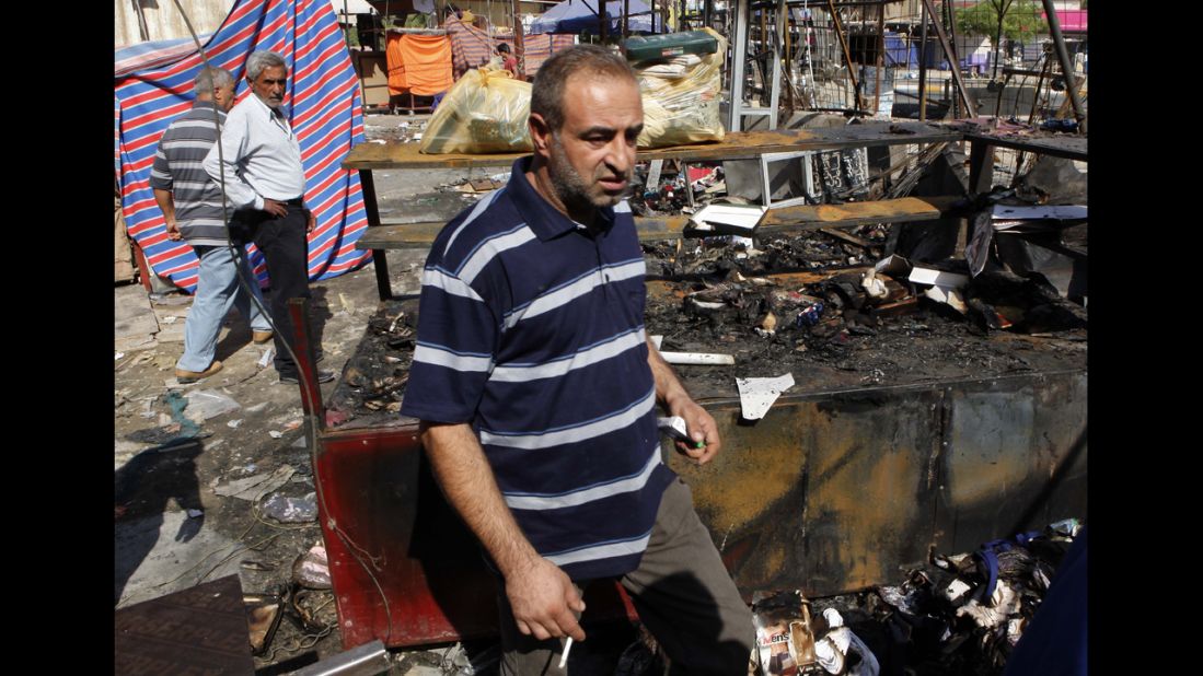 People inspect the scene of a bombing at a store in Baghdad on August 11.