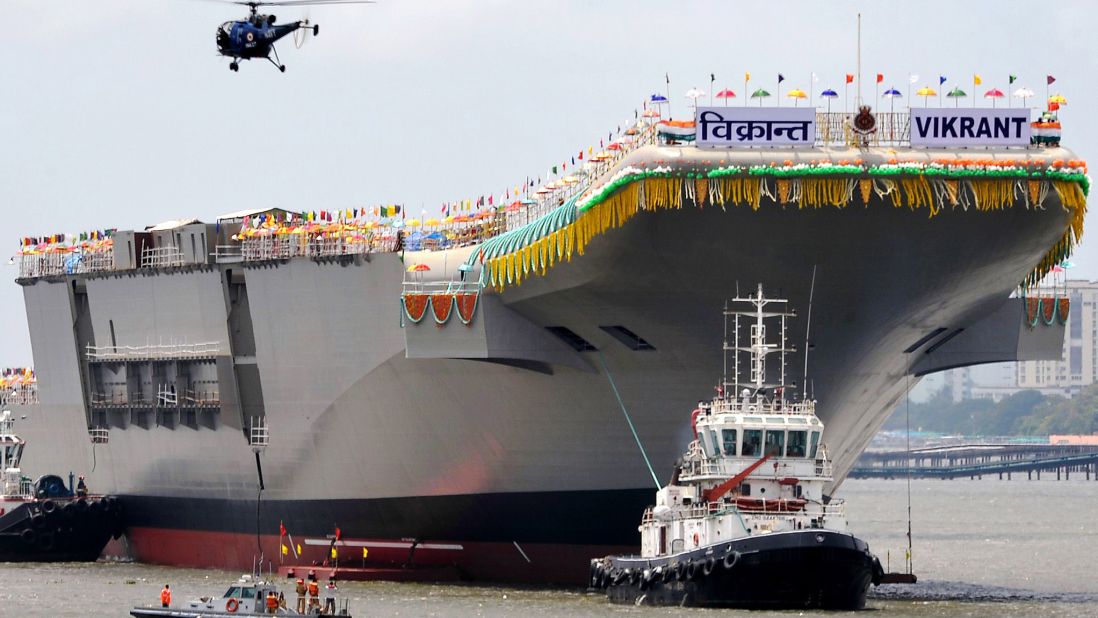 Tugboats guide aircraft carrier INS Vikrant as it leaves the Cochin Shipyard after the launch ceremony in Kochi, India, on Monday, August 12, 2013. India's carrier is one-third the size of U.S. Navy's Nimitz class carriers.