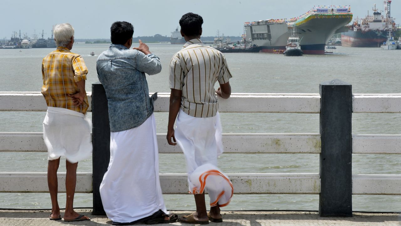 People watch as the INS Vikrant leaves Cochin Shipyard on August 12.
