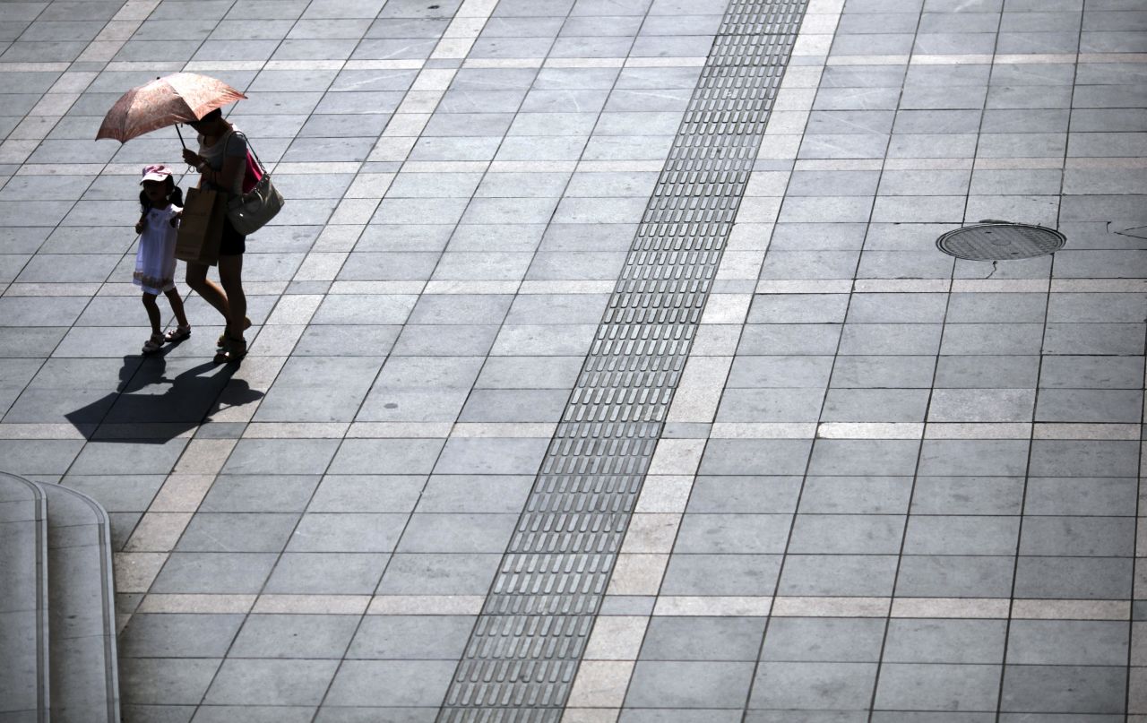 A woman and a girl walk under an umbrella during <a href="http://www.cnn.com/2013/08/13/world/asia/asia-heat/index.html">a scorching summer heat wave</a> in Shanghai, China, on August 13.