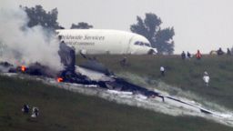 Debris burns as a UPS cargo plane lies on a hill at Birmingham-Shuttlesworth International Airport after crashing on approach, Wednesday, Aug. 14, 2013, in Birmingham, Ala. Toni Herrera-Bast, a spokeswoman for Birmingham's airport authority, says there are no homes in the immediate area of the crash. (AP Photo/Hal Yeager)