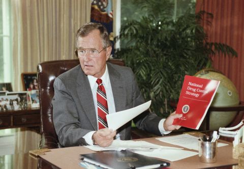President George H. Bush holds up a copy of the National Drug Control Strategy during a meeting in the Oval Office on September 5, 1989. In a televised address to the nation, Bush asked Americans to join the war on drugs.
