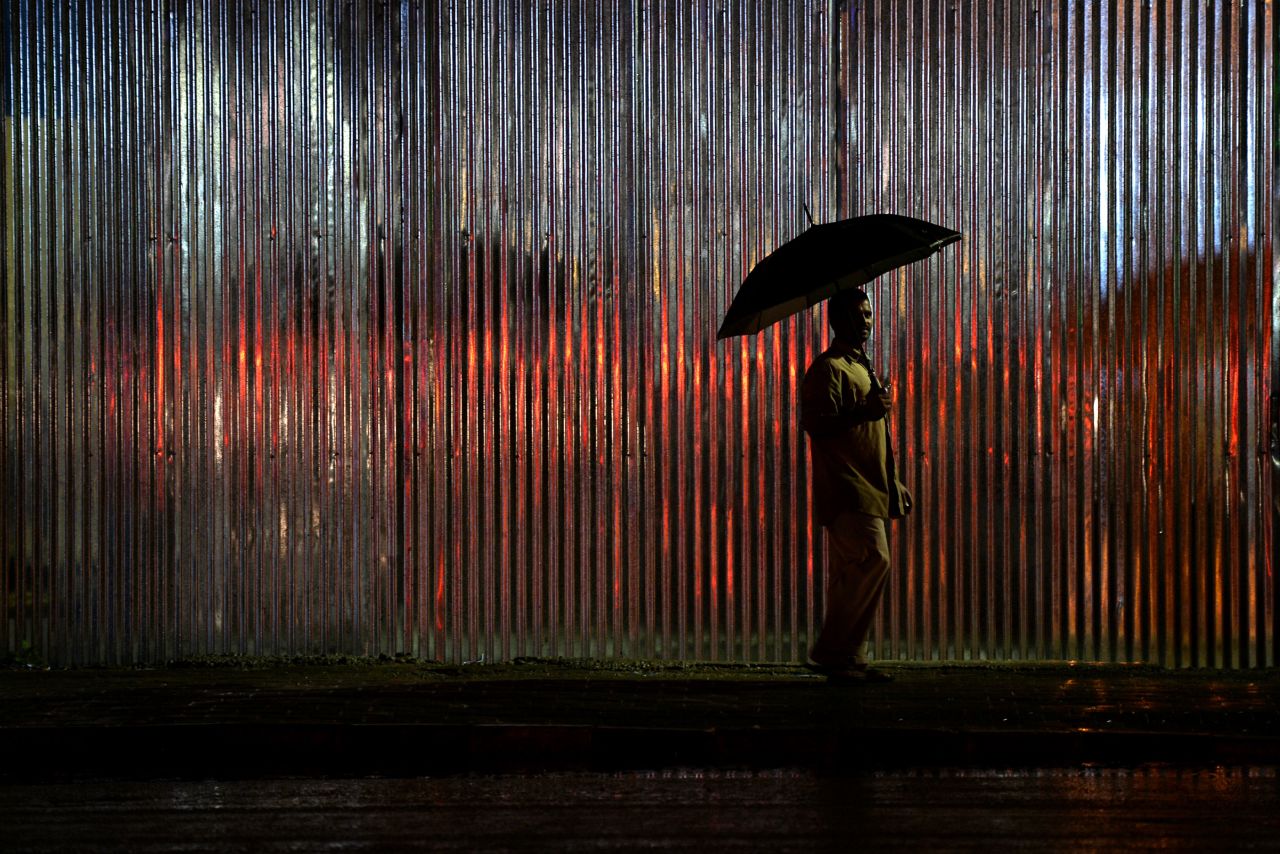 A pedestrian walks with an umbrella as rain falls in Bangalore, India, on Wednesday, August 14.