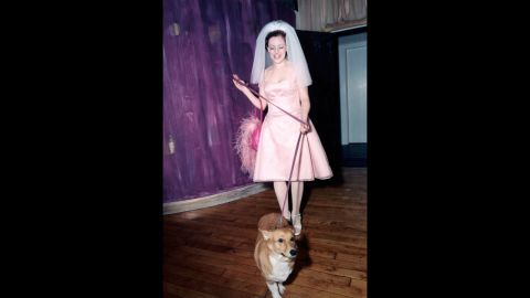 This bride poses in a pink wedding dress holding on to her pet corgi.