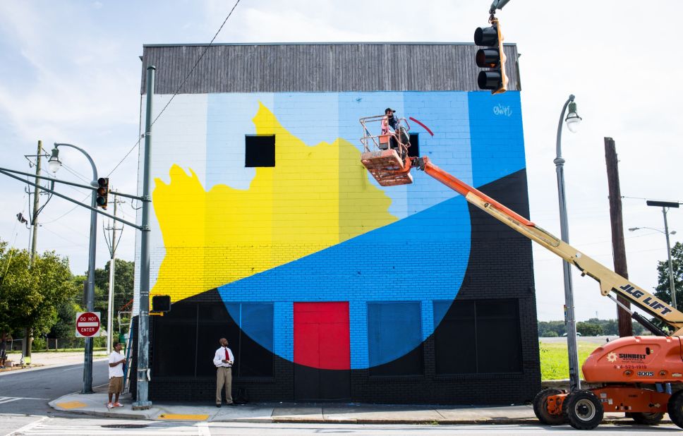 An artist hitches a ride to the top of a wall. Twenty artists converged on Atlanta this month as part of an annual street art conference called Living Walls. 
