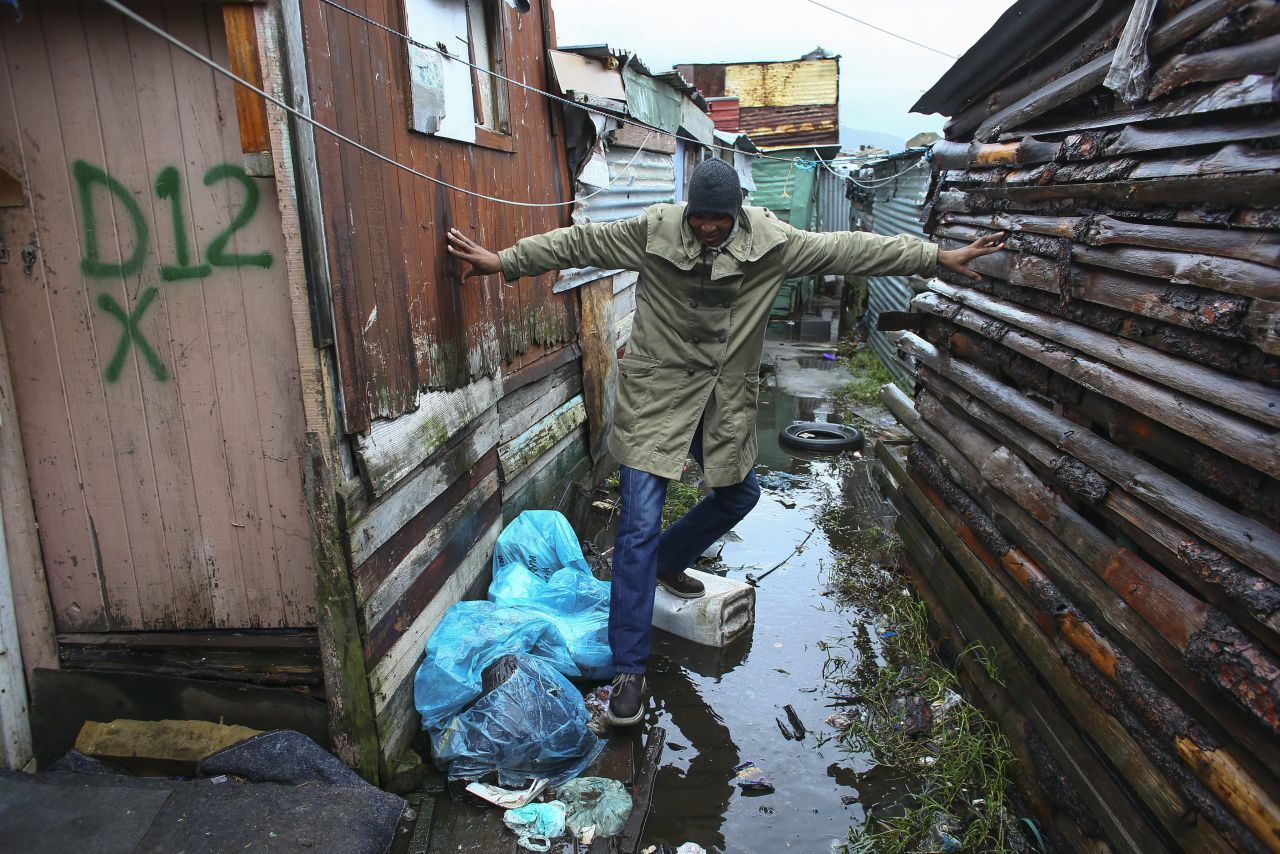A man threads his way between homes in the flooded informal shack settlement of Masiphumelele in Cape Town, South Africa, on August 15.