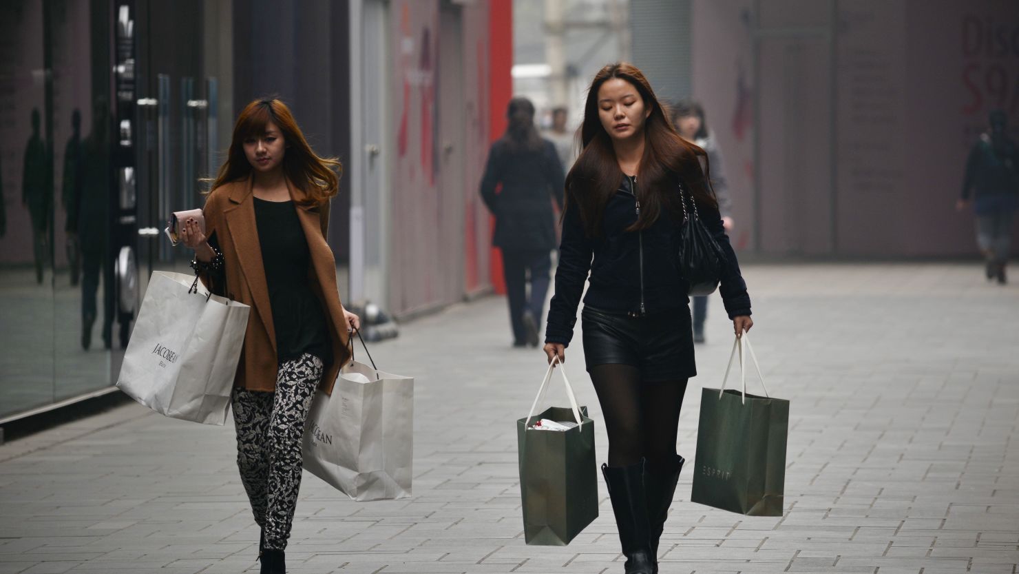 Two women walk with shopping bags in Beijing, China, on April 23.