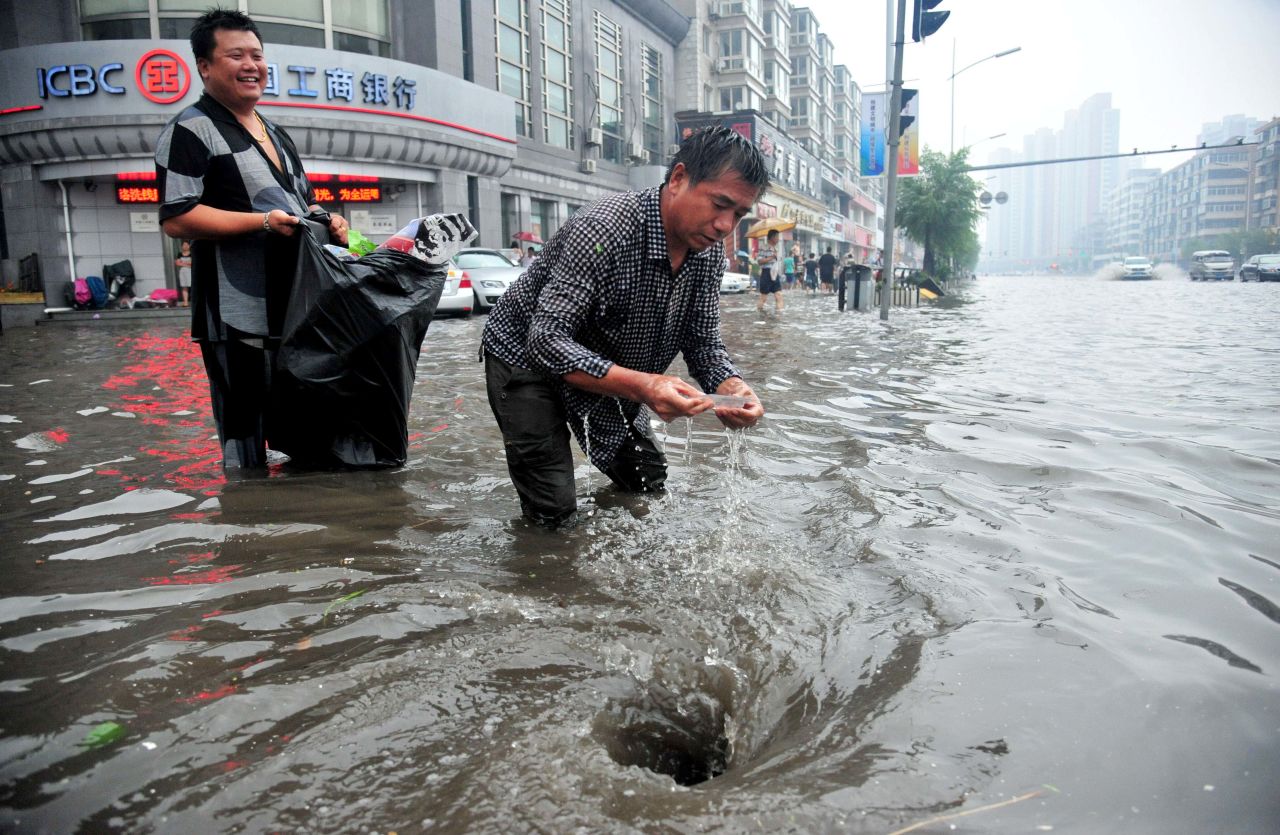 Two men clear a blocked catch basin on a street in Shenyang, the capital of northeast China's Liaoning Province, on August 16.