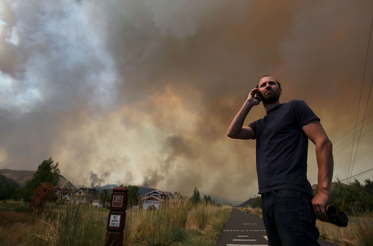 Kevin Bullock, of Bellevue, Idaho, talks on a cell phone as smoke from the wildfire envelops a neighborhood. 