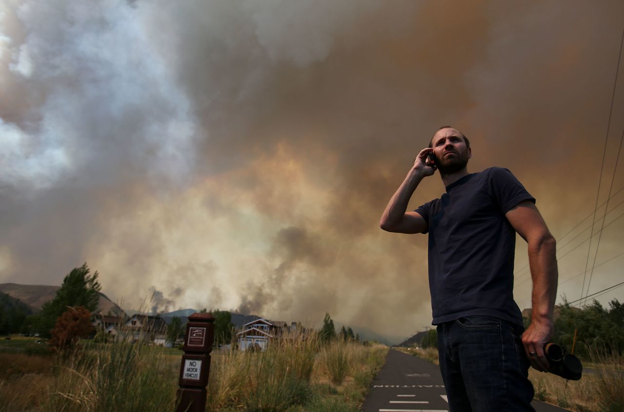 Kevin Bullock, of Bellevue, Idaho, talks on a cell phone as smoke from the wildfire envelops a neighborhood.