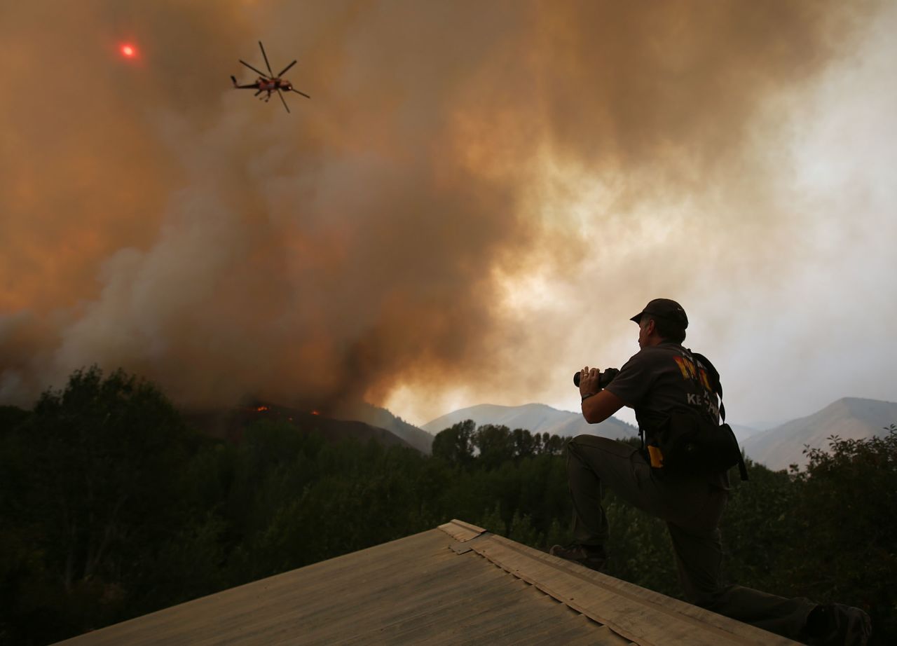 John Koth climbs to the roof of a neighbor's house near Hailey to photograph the blaze on August 16.