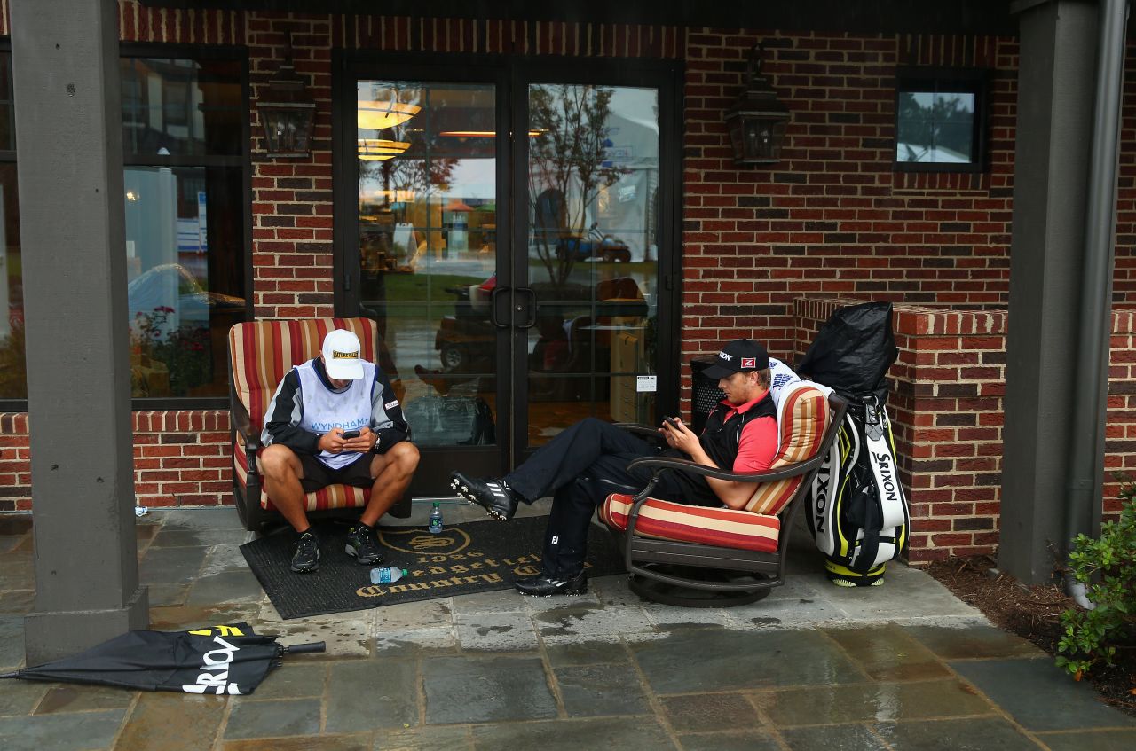 Chris Stroud, right, and his caddie check their phones during a weather delay on August 17 in the third round of the Wyndham Championship in Greensboro, North Carolina.